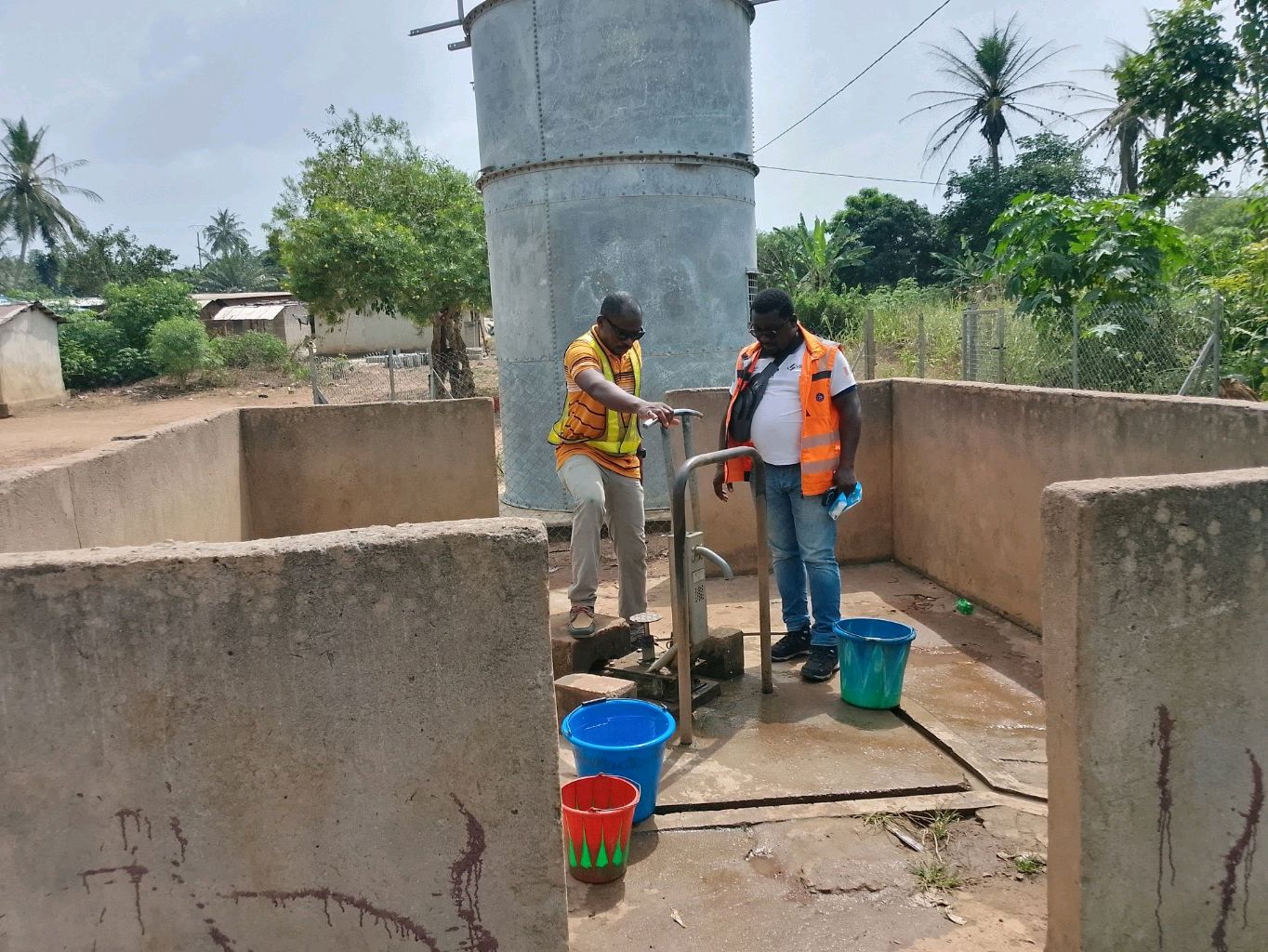 Test d'une pompe à eau manuelle par deux techniciens dans une enceinte bétonnée